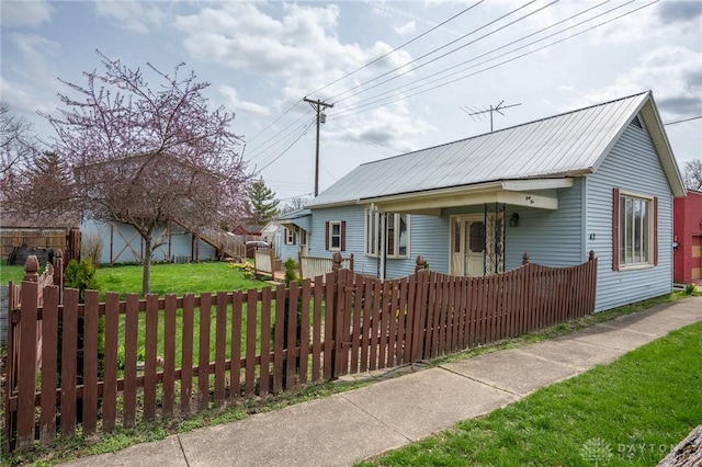 view of front of property featuring a front lawn, a fenced front yard, and metal roof