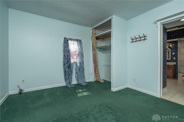 unfurnished bedroom featuring a textured ceiling, carpet flooring, and baseboards