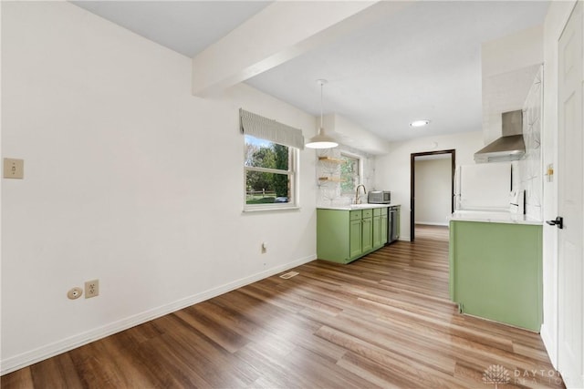 kitchen with light countertops, green cabinets, light wood-type flooring, wall chimney range hood, and baseboards