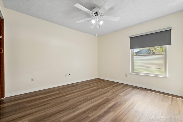 unfurnished room with baseboards, visible vents, wood finished floors, and ceiling fan