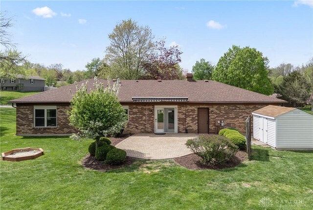 rear view of house with a lawn, a patio area, a shed, and brick siding