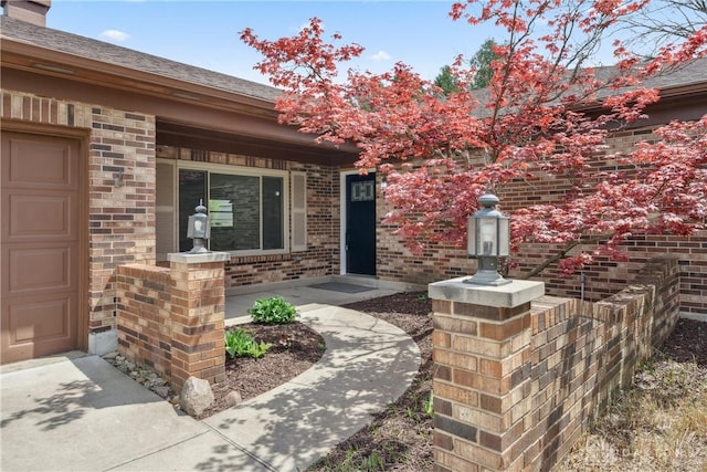 entrance to property featuring an attached garage, a porch, and brick siding