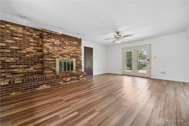 unfurnished living room featuring baseboards, wood finished floors, ceiling fan, and rail lighting