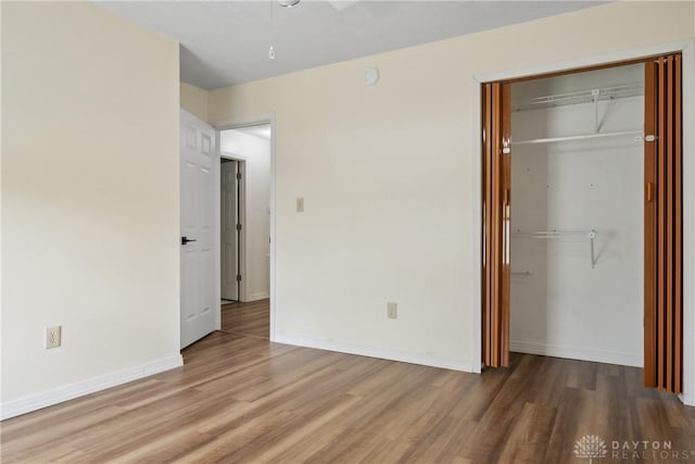 unfurnished bedroom featuring a closet, ceiling fan, wood finished floors, and baseboards