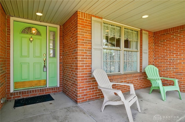 doorway to property with covered porch and brick siding