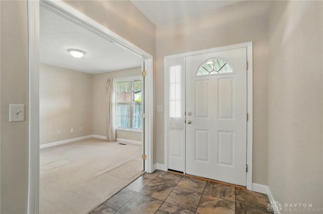 carpeted entrance foyer with a healthy amount of sunlight and baseboards