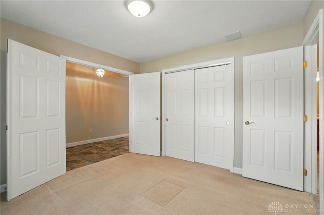 unfurnished bedroom with a closet, carpet flooring, baseboards, and visible vents