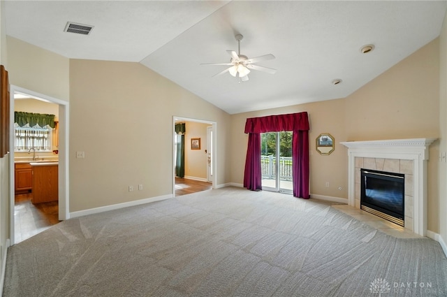 unfurnished living room featuring a fireplace, ceiling fan, visible vents, vaulted ceiling, and light colored carpet