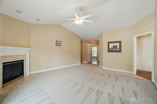 unfurnished living room featuring light colored carpet, baseboards, vaulted ceiling, a tiled fireplace, and a ceiling fan