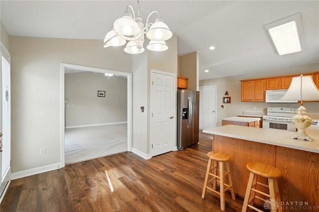 kitchen featuring a notable chandelier, white appliances, a peninsula, light countertops, and lofted ceiling