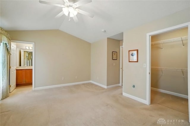 unfurnished bedroom featuring a closet, light colored carpet, lofted ceiling, and a spacious closet