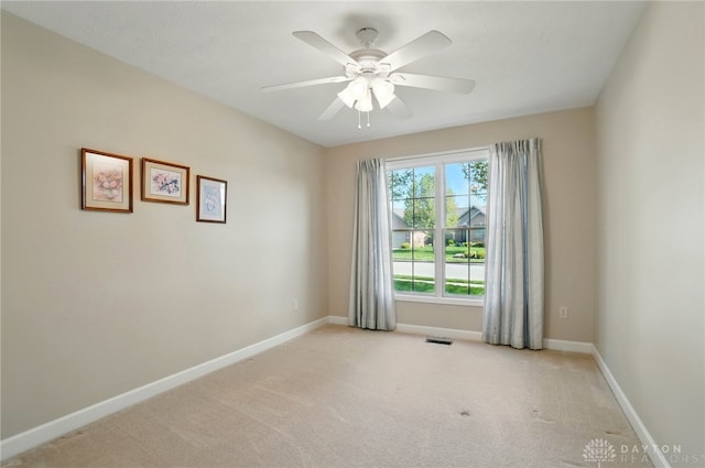 spare room with visible vents, baseboards, a ceiling fan, and light carpet