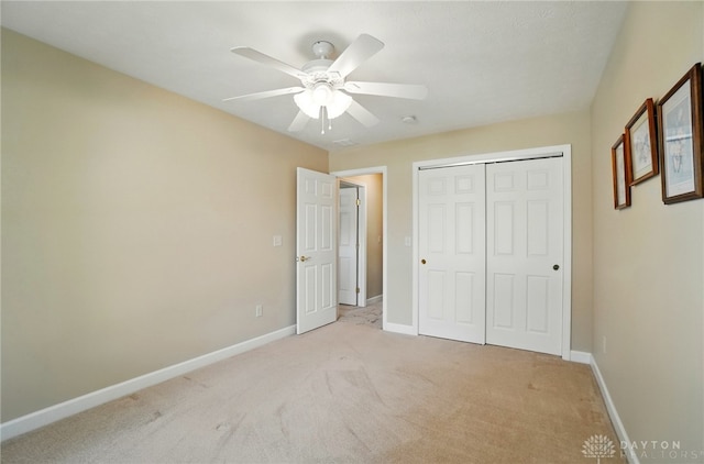 unfurnished bedroom featuring a closet, a ceiling fan, light colored carpet, and baseboards