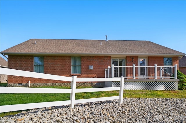 back of house with a deck, brick siding, fence, and roof with shingles