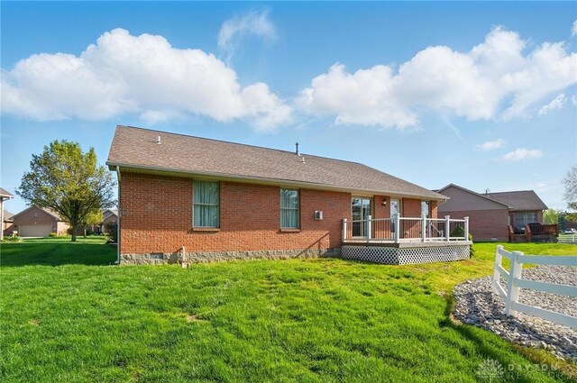rear view of house with a deck, brick siding, and a yard