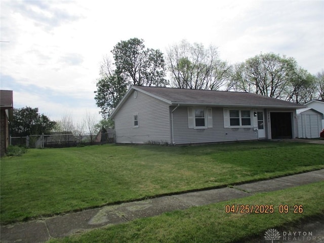 view of front of property with a front yard, a storage unit, an attached garage, and fence