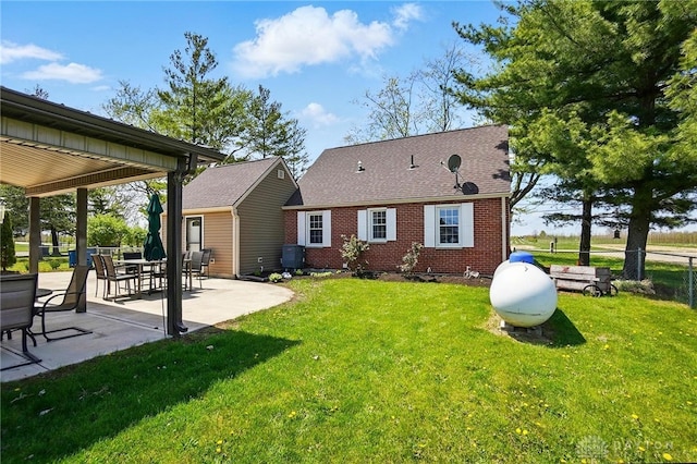 back of house featuring a yard, brick siding, fence, roof with shingles, and a patio area