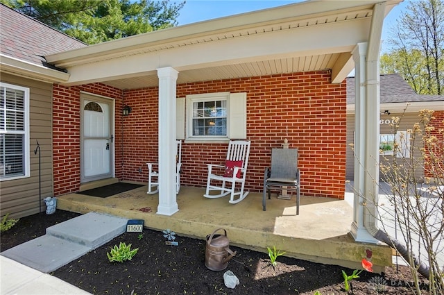 property entrance featuring covered porch and brick siding