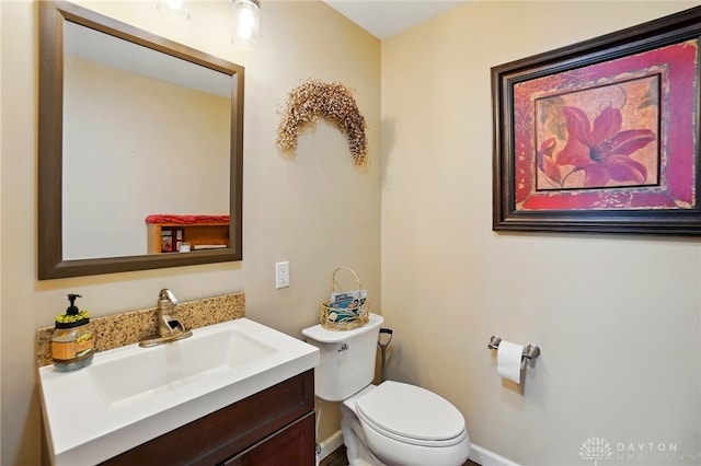 half bathroom with toilet, vanity, and baseboards
