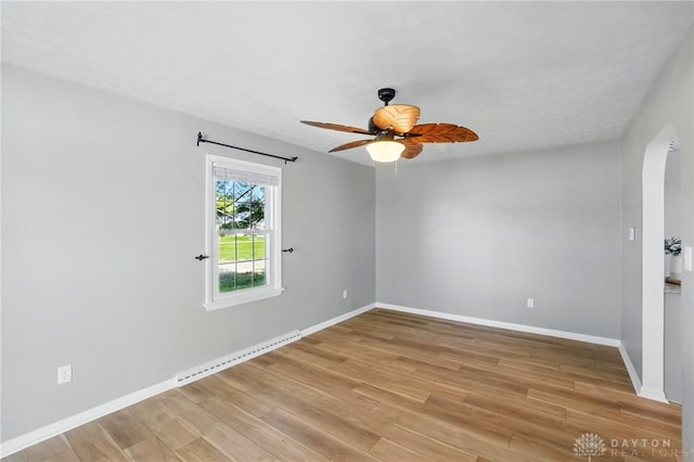unfurnished room with baseboard heating, baseboards, a ceiling fan, and light wood finished floors