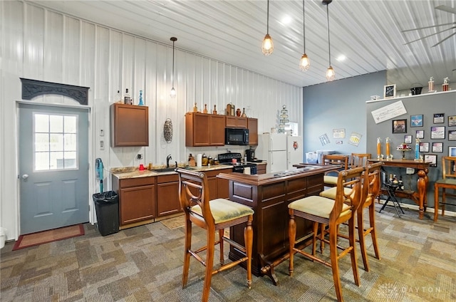 kitchen featuring freestanding refrigerator, brown cabinetry, electric range, light countertops, and black microwave