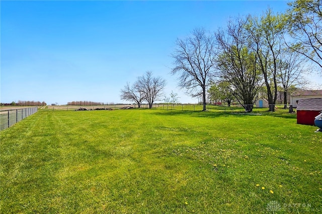 view of yard with fence and a rural view