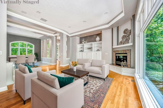 living area featuring baseboards, visible vents, wood finished floors, and a glass covered fireplace