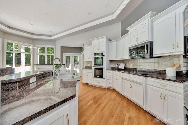 kitchen with a sink, white cabinetry, stainless steel appliances, and a tray ceiling