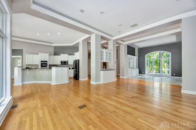 unfurnished living room with visible vents, light wood-type flooring, and crown molding
