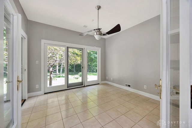 empty room with ceiling fan, visible vents, baseboards, light tile patterned flooring, and vaulted ceiling