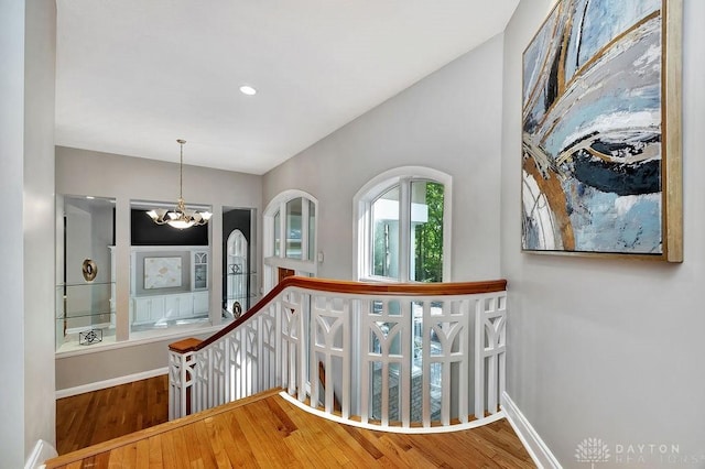 stairs featuring an inviting chandelier, wood finished floors, and baseboards