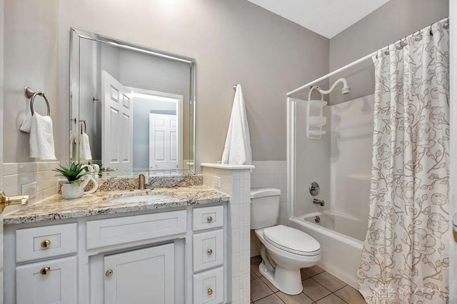 full bath with shower / bath combo, tile walls, vanity, tile patterned floors, and toilet