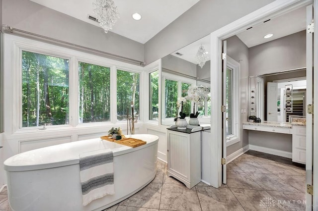 full bathroom featuring an inviting chandelier, visible vents, vanity, and a soaking tub