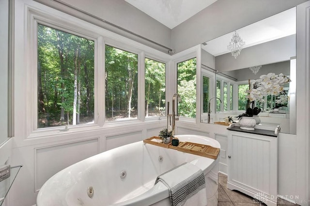 bathroom with an inviting chandelier, a healthy amount of sunlight, tile patterned floors, and a jetted tub