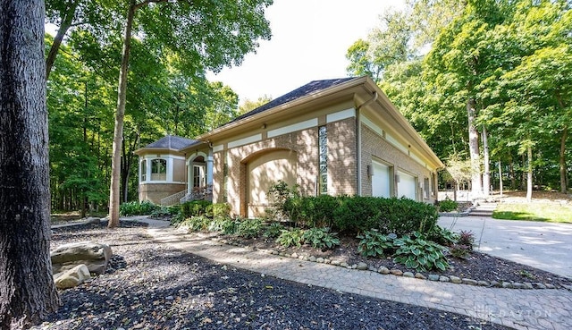 exterior space featuring brick siding, concrete driveway, and an attached garage