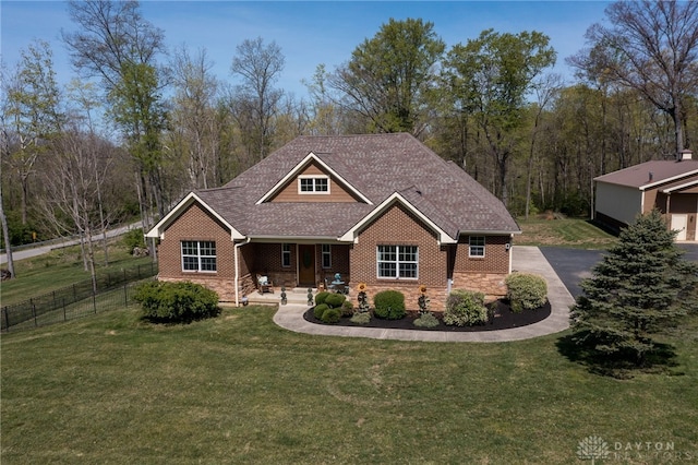 craftsman inspired home featuring fence, covered porch, a front yard, brick siding, and a shingled roof