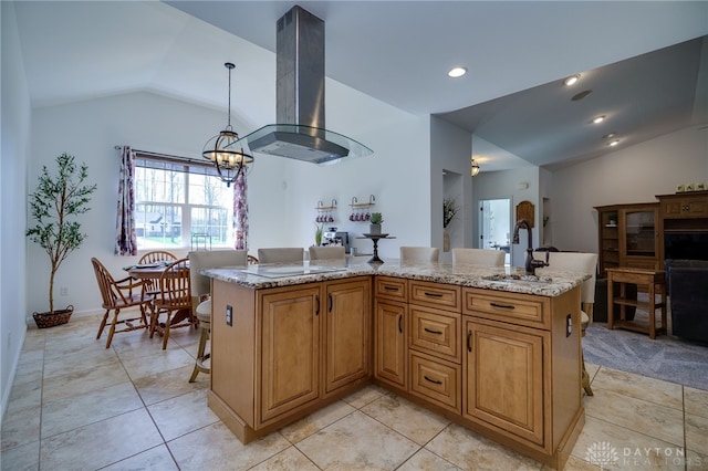 kitchen with pendant lighting, light stone countertops, island exhaust hood, a sink, and vaulted ceiling