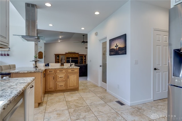 kitchen with ceiling fan, light stone counters, island exhaust hood, and visible vents
