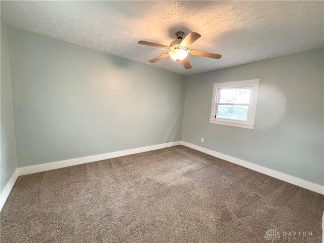 spare room with dark carpet, a textured ceiling, ceiling fan, and baseboards