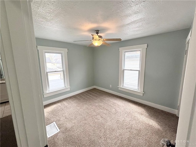 empty room with a wealth of natural light, visible vents, and baseboards