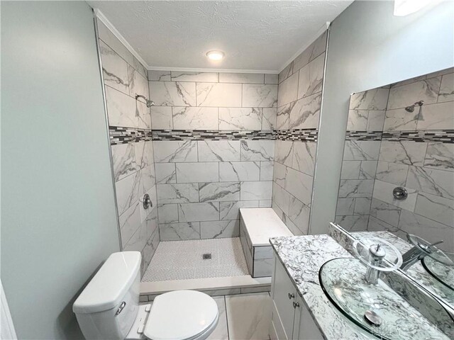 bathroom featuring vanity, toilet, a tile shower, marble finish floor, and a textured ceiling