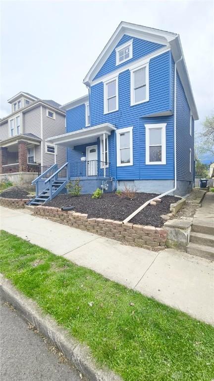 view of front of property featuring stairway and a porch