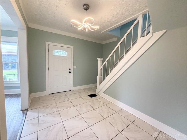 entryway featuring an inviting chandelier, a textured ceiling, stairway, and baseboards