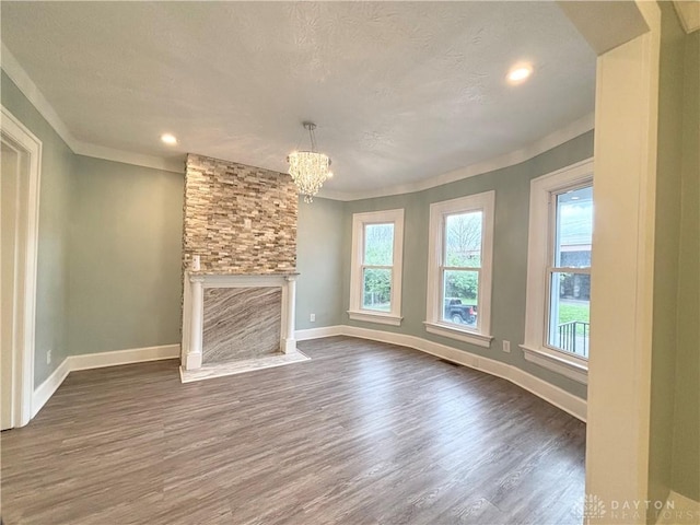 unfurnished living room with an inviting chandelier, dark wood-style flooring, a textured ceiling, and baseboards
