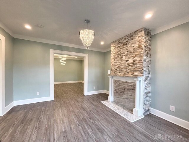 unfurnished living room featuring a notable chandelier, wood finished floors, and baseboards
