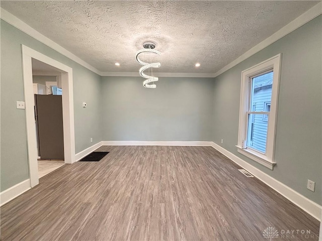 empty room with crown molding, dark wood-style floors, a textured ceiling, and baseboards