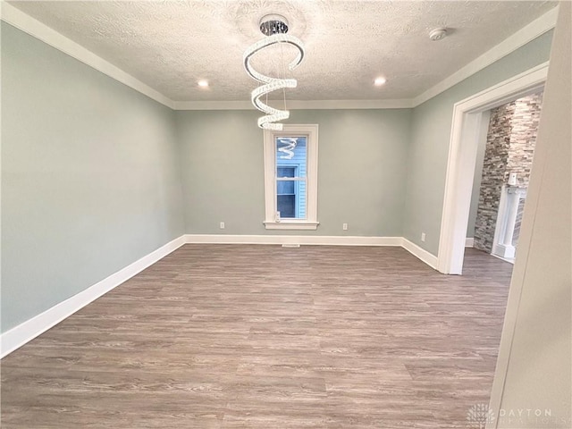 empty room featuring crown molding, dark wood-style floors, a textured ceiling, and baseboards