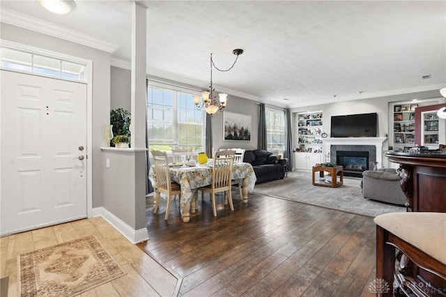 foyer entrance featuring an inviting chandelier, a tile fireplace, hardwood / wood-style flooring, and crown molding
