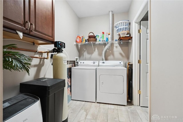 washroom featuring cabinet space, washing machine and clothes dryer, and light wood-type flooring
