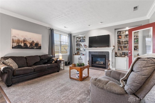 carpeted living area with a textured ceiling, a tiled fireplace, ornamental molding, and built in features
